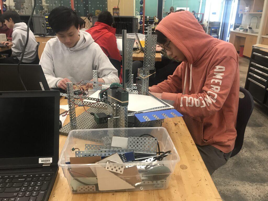 Seniors Morris Yu and Blake Zhou work on their paper airplane folding machine.