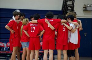 Varsity volleyball coach Lori Gragnola in a huddle with the boys’ team.
