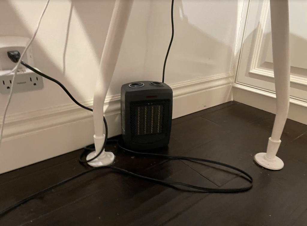 My space heater sitting comfortably under my table.