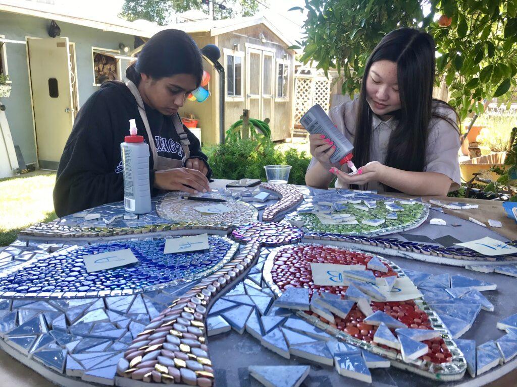  Juniors Sunny Huang and Aanika Jain glue tesserae onto their flower mosaic. 