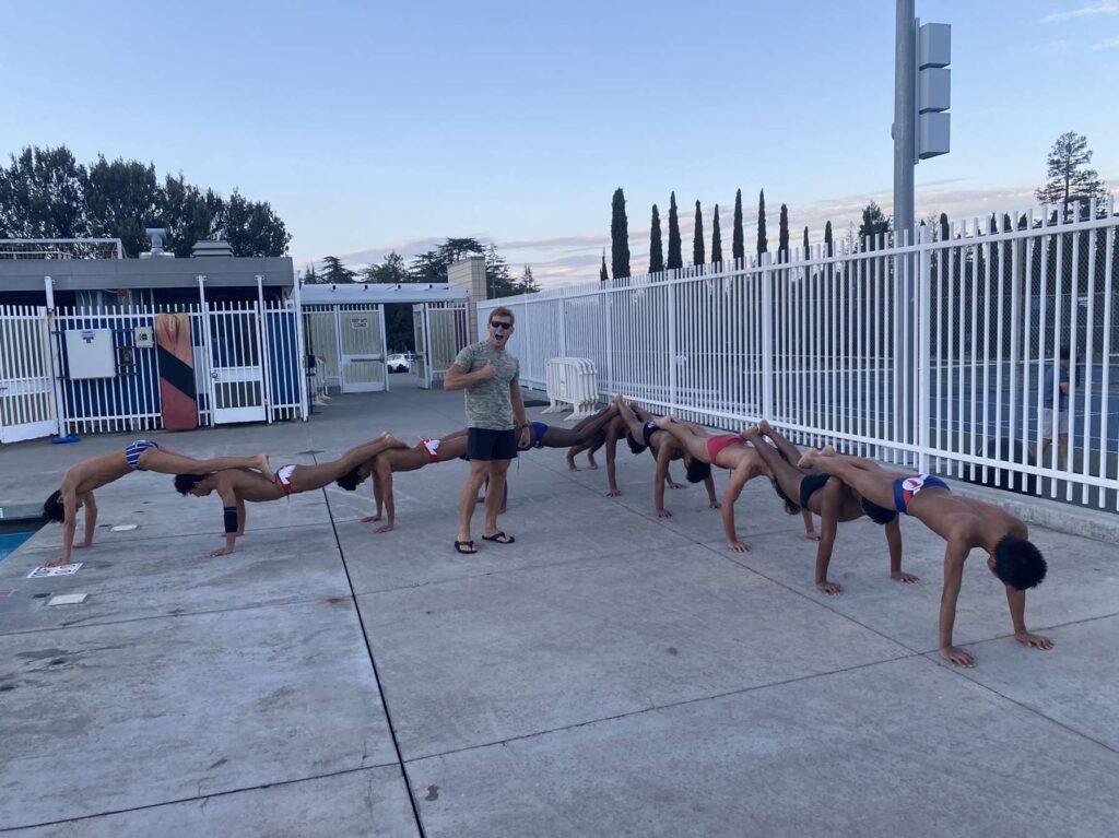 Head coach Kendal Jarvis smiles as the team creates a plank centipede.