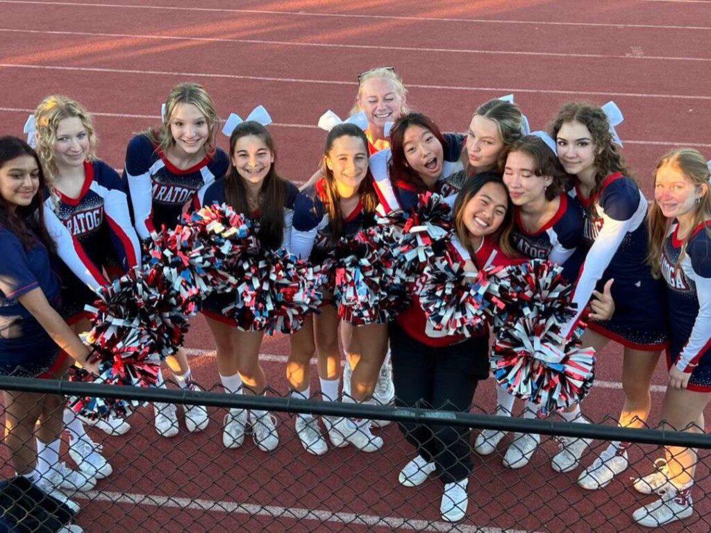 Before beginning cheering for a varsity football game, the team takes a photo together