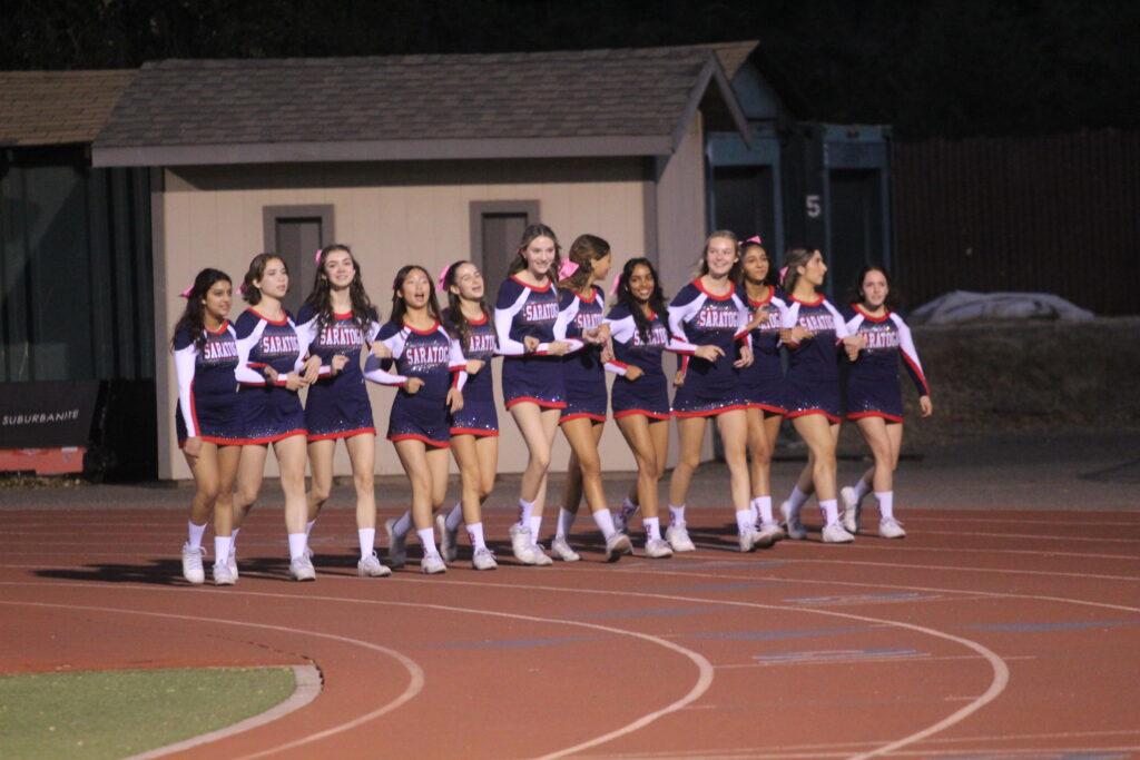 The cheer team walks together along the track before the football game.