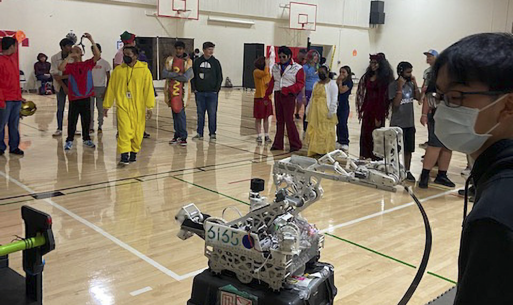 Students at the Halloween Party gather around the robot demonstration organized by the Best Buddies club.