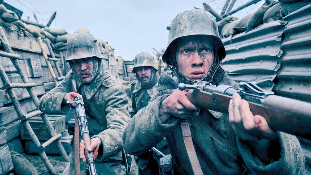 Paul Bäumer, Katczinsky and another soldier survey a trench with rifles at the ready in Netflix’s All Quiet on the Western Front.