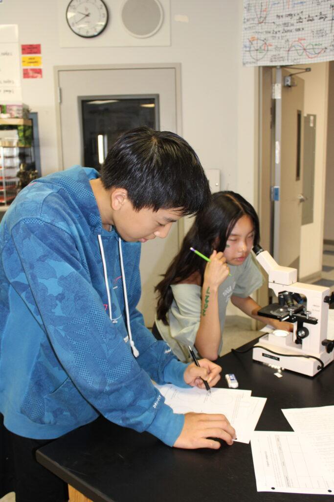 Students+in+biology+class+peer+into+a+microscope+and+record+their+observations.