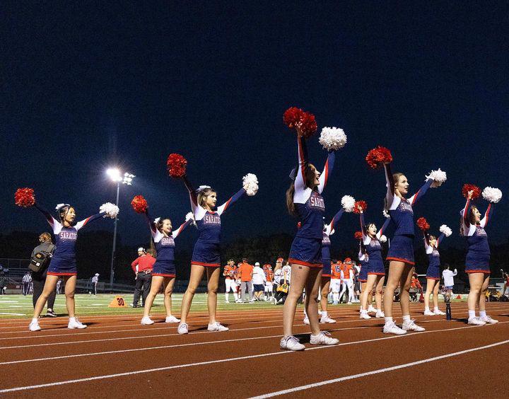 The cheer team enthusiastically cheers for our football team.