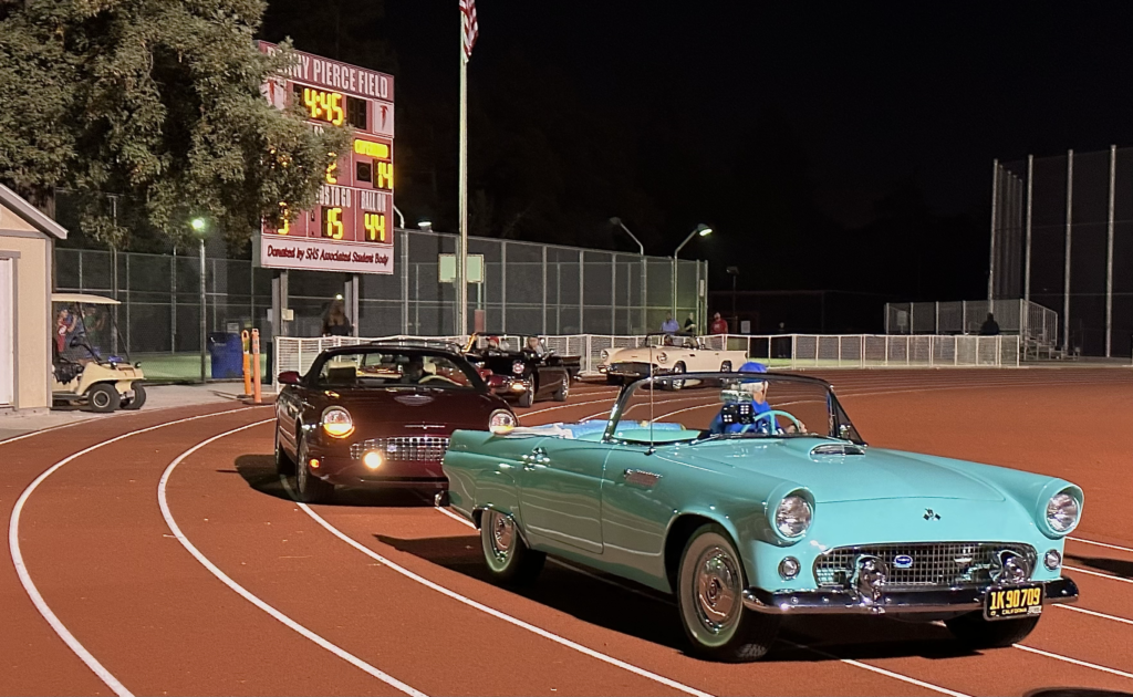 The cars at the homecoming halftime show line up while waiting for the homecoming court to be escorted into their cars.
