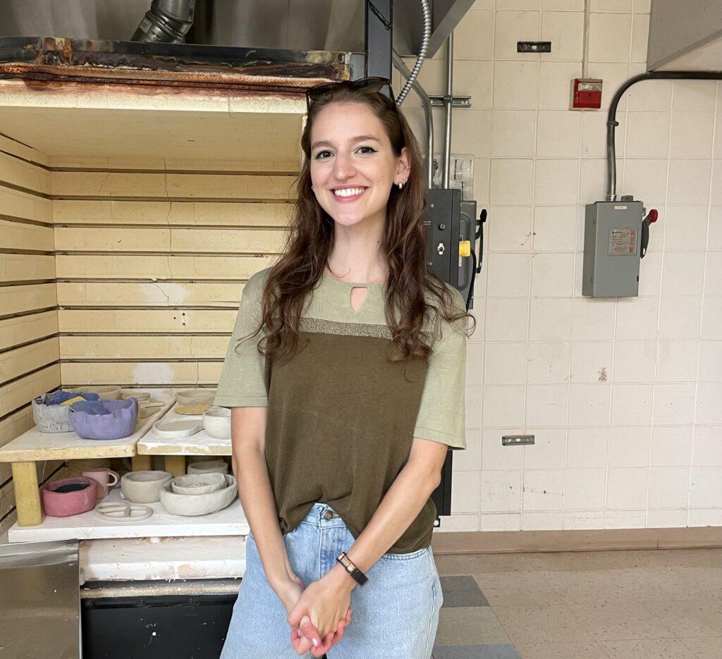 Art teacher Nikki Rodriguez stands in front of her kiln containing the clay works of many students in her ceramics class.