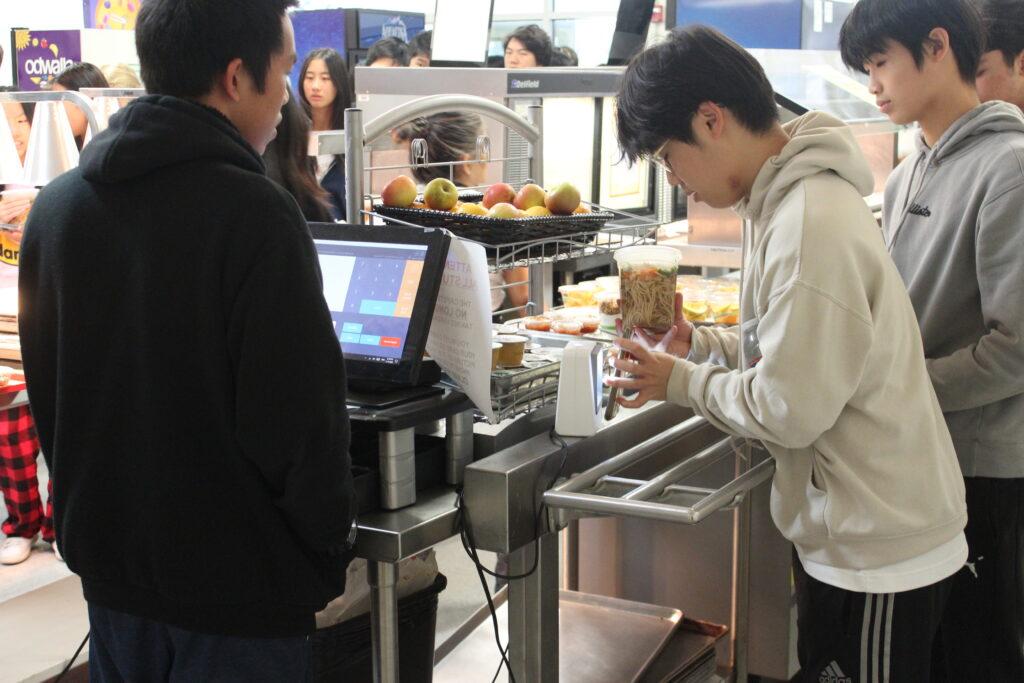 Junior Kirby Fung, who regularly volunteers as a lunch line cashier, watches as students scan their ID cards to get food on Nov. 14.