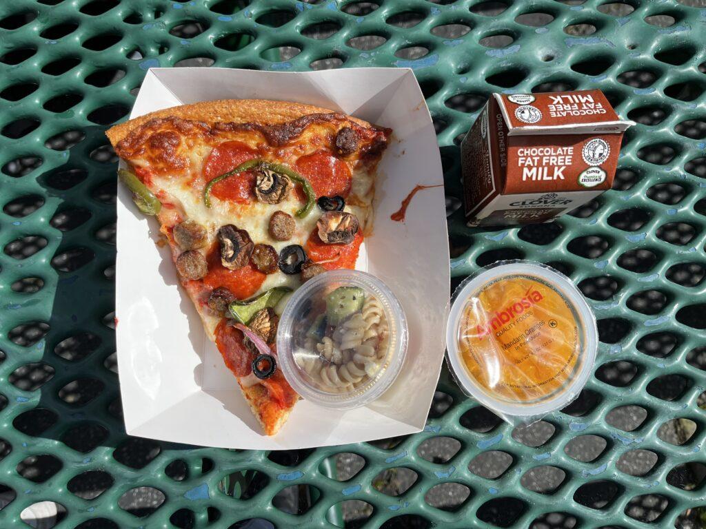 A scrumptious pizza with a side of chocolate milk and fruit cups. 