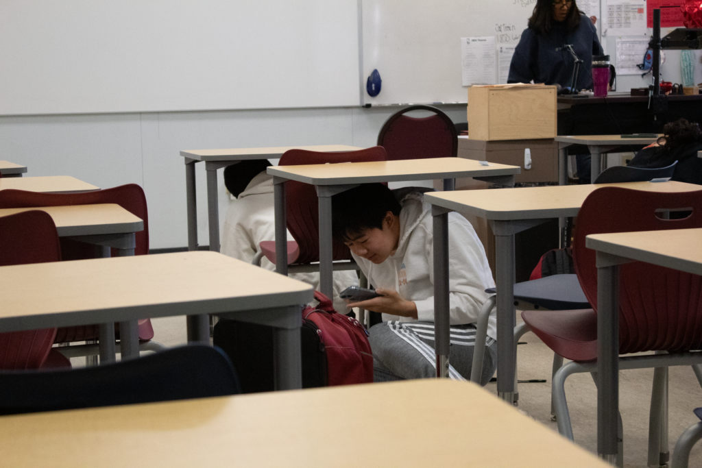 Junior Alan Lu ducks and covers during the earthquake drill. 