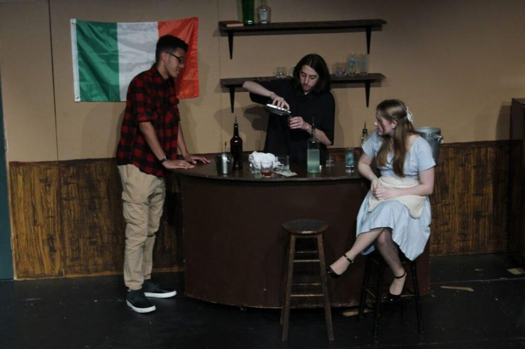 Senior Ryan Cagliostro (young Jamie) mixes up a shot for a drinking game with junior Ryan Backhus (future Jamie) and junior Chloe Mantle (young Abby) in the play “Now and Then.”