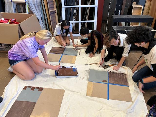Students collaborate for a scenetic painting project to learn how to paint bricks, wood, and marble.