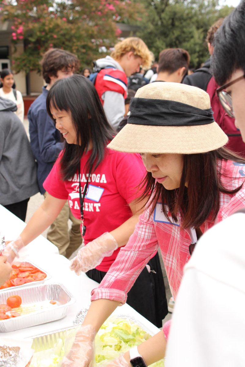 Parent volunteers help serve condiments to the students.