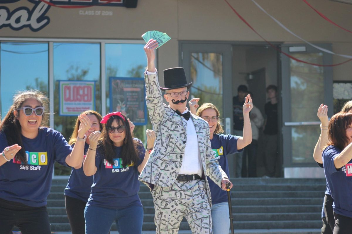 English teacher Jason Friend holds up money to the song “Money, Money, Money” by ABBA. The homecoming theme for the staff this year was “The Game of Life.”