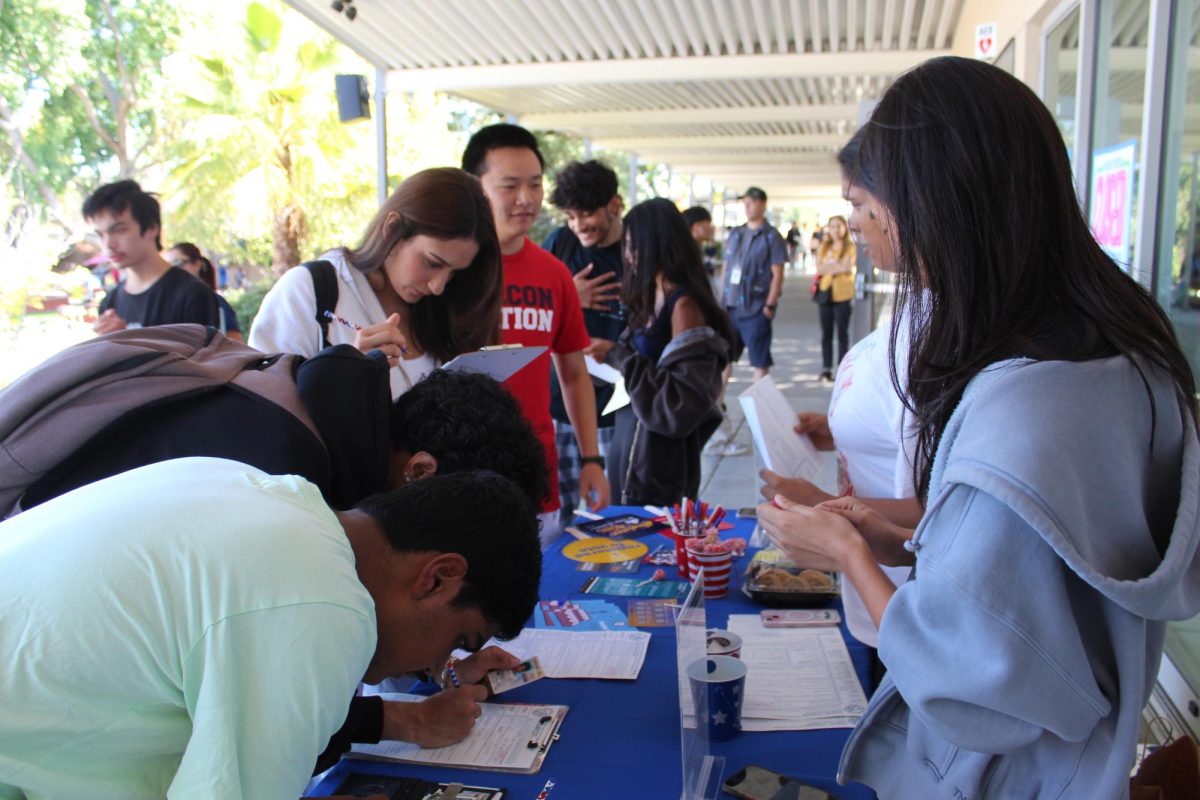 Students gather around the table at the top of the quad steps during the voter registration drive on Sept. 25.
