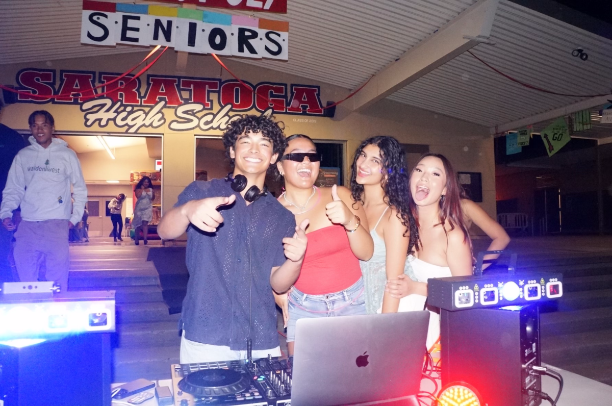 Seniors Angie Chen, Sydney Li, Anisa Taymuree and Homecoming DJ, D-Flo, pose for a photo in front of the newly decorated student center.
