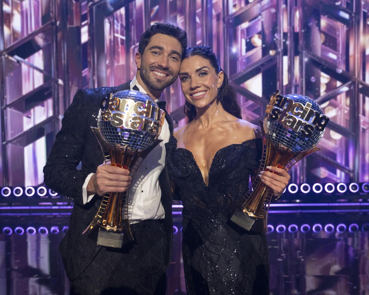 Graziadei and Johnson smiling ear to ear, holding their mirrorball trophies after winning season 33 of DWTS.
