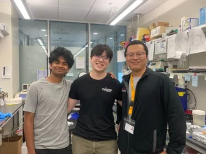 Junior Arjun Krish, Class of `23 alumnus Adam Xu and his mentor Dr. Liang Li stand in front of Krish’s lab station in the summer of 2024.