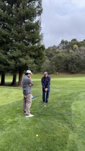 Gragnola coaches senior Aidan Smith on how to hit a difficult shot from the rough before the boys’ golf match at the Saratoga Country Club on March 17.
